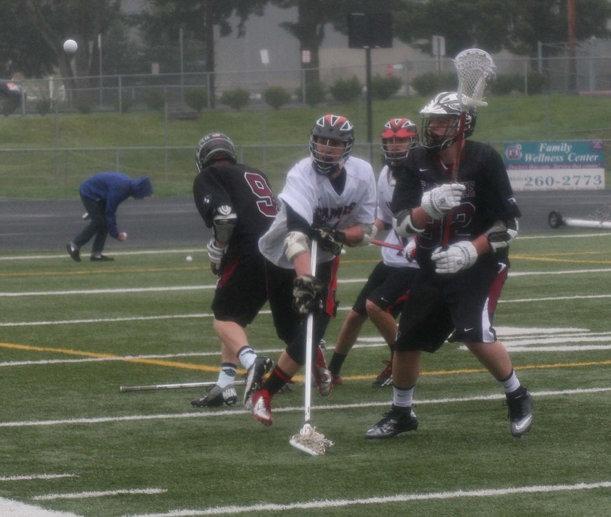 Zach Quist slings the ball away from two Eastlake lacrosse players, at Doc Harris Stadium.