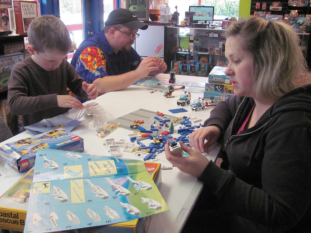 Dave and Becky Dotson, and their son David Jr., enjoy playing with Legos at their new store in Washougal, Hero Support. The business, which opened today, buys, sells and trades Pokemon, Yu-Gi-Oh and Magic: The Gathering cards, and sells role playing games and Star Wars, Simpsons and Avengers collectible figures.