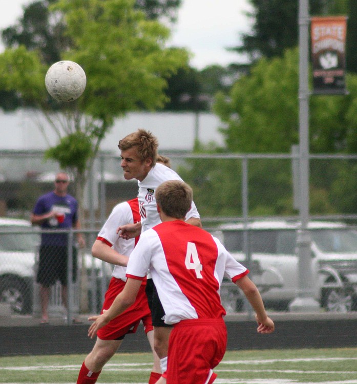 Camas defender Sam Pizot gets between two Ferris players and heads the ball forward for the Papermakers.