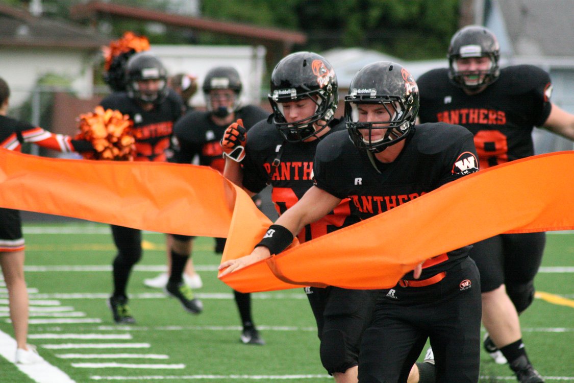 The Washougal High School football players break the ticker tape on their new field turf Friday, at Fishback Stadium. The Panthers beat Hudson's Bay 35-0.