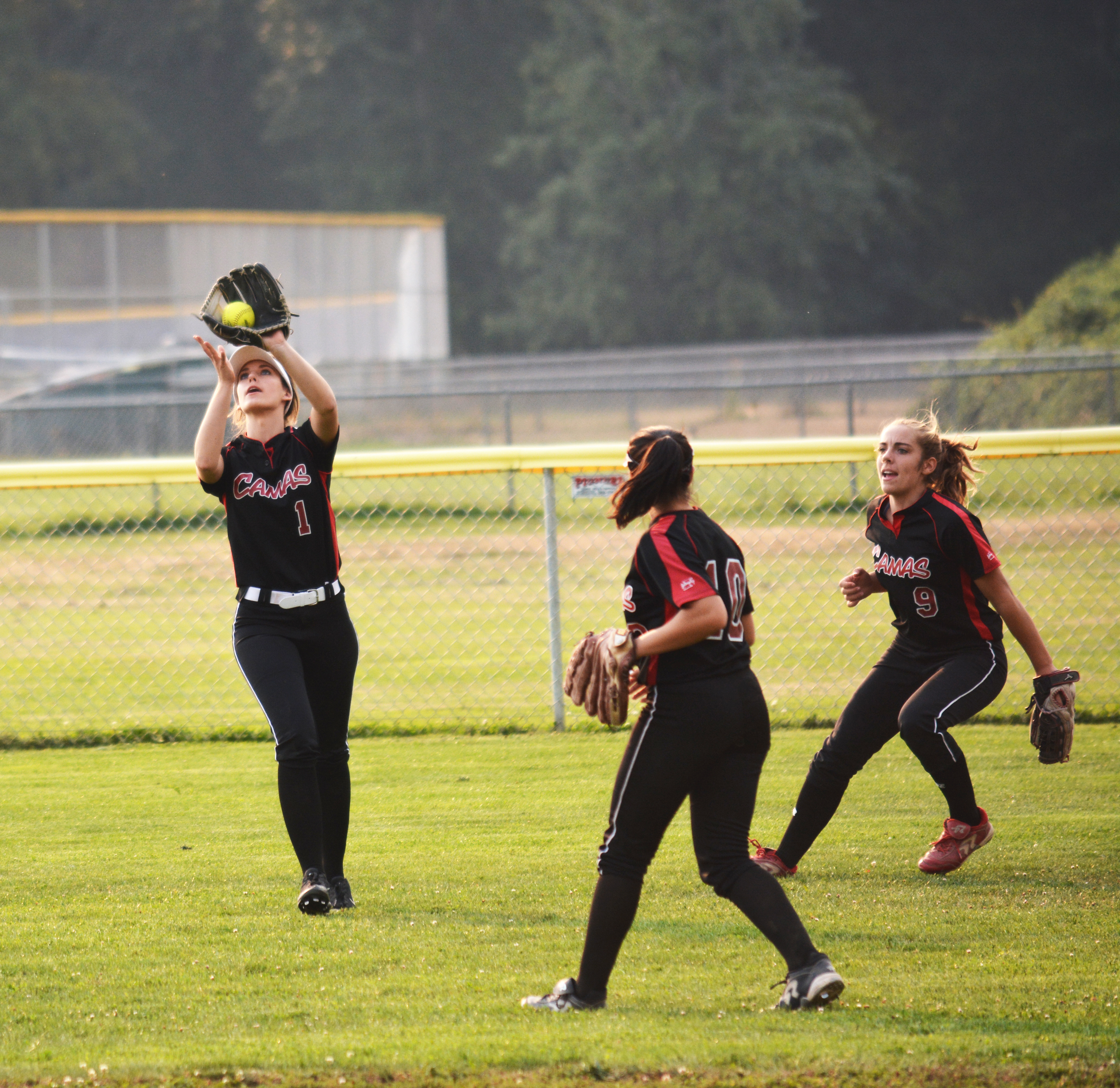Camas High School senior Payton Bates catches a fly ball in left field for the Papermakers, while Sophie Franklin (right) and Taija Souki provide assistance. Defense has been key to Camas' 22-0 record this season. 