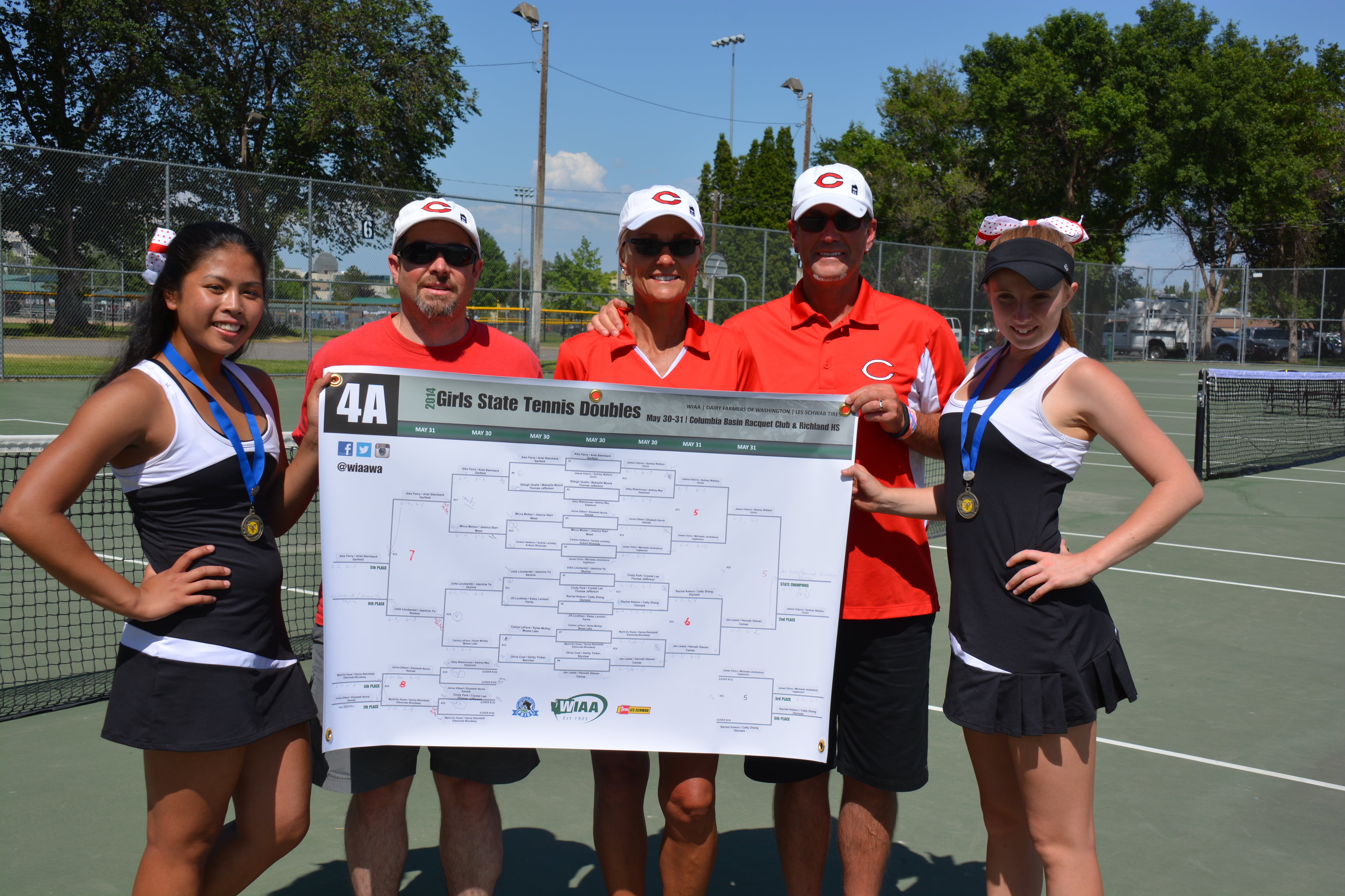 Camas doubles tennis champions Hannah Gianan and Jen Lewis hold up the tournament bracket with coaches Jonathan Burton and Annie and Craig Sumpter.