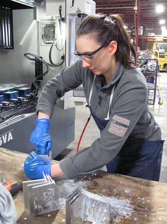 Denise Fretwell, a machinist at Micro Machining LLC, finishes parts that will be machine-dated with the month and year they were manufactured.  The company, which makes precision metal parts such as shafts, spindles, handles and nuts, is located in Building 4 in the Port of Camas-Washougal Industrial Park.