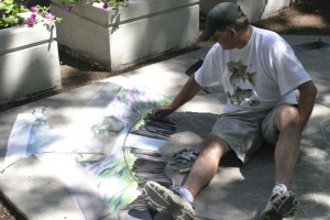 Sidewalk chalk artist Steve Platt begins a painting in front of the Liberty Theater building in downtown Camas on Friday.  Platt, a Camas native, returned to his hometown to make an appearance during the Camas Days festival. The painting was completed by the end of the day on Friday.