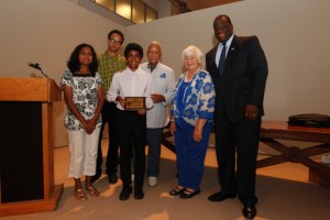 Varun Medhal (center with plaque), stands with his mom, Vidyavathi and other dignitaries from the United States Tennis Assocation. Varun was honored with a weekend trip to New York City for his essay on famous tennis player Arthur Ashe's greatest accomplishment.