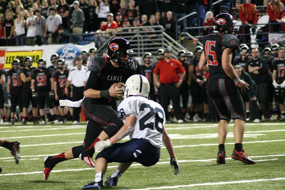 Camas quarterback Reilly Hennessey keeps the ball and moves it forward for a first down.