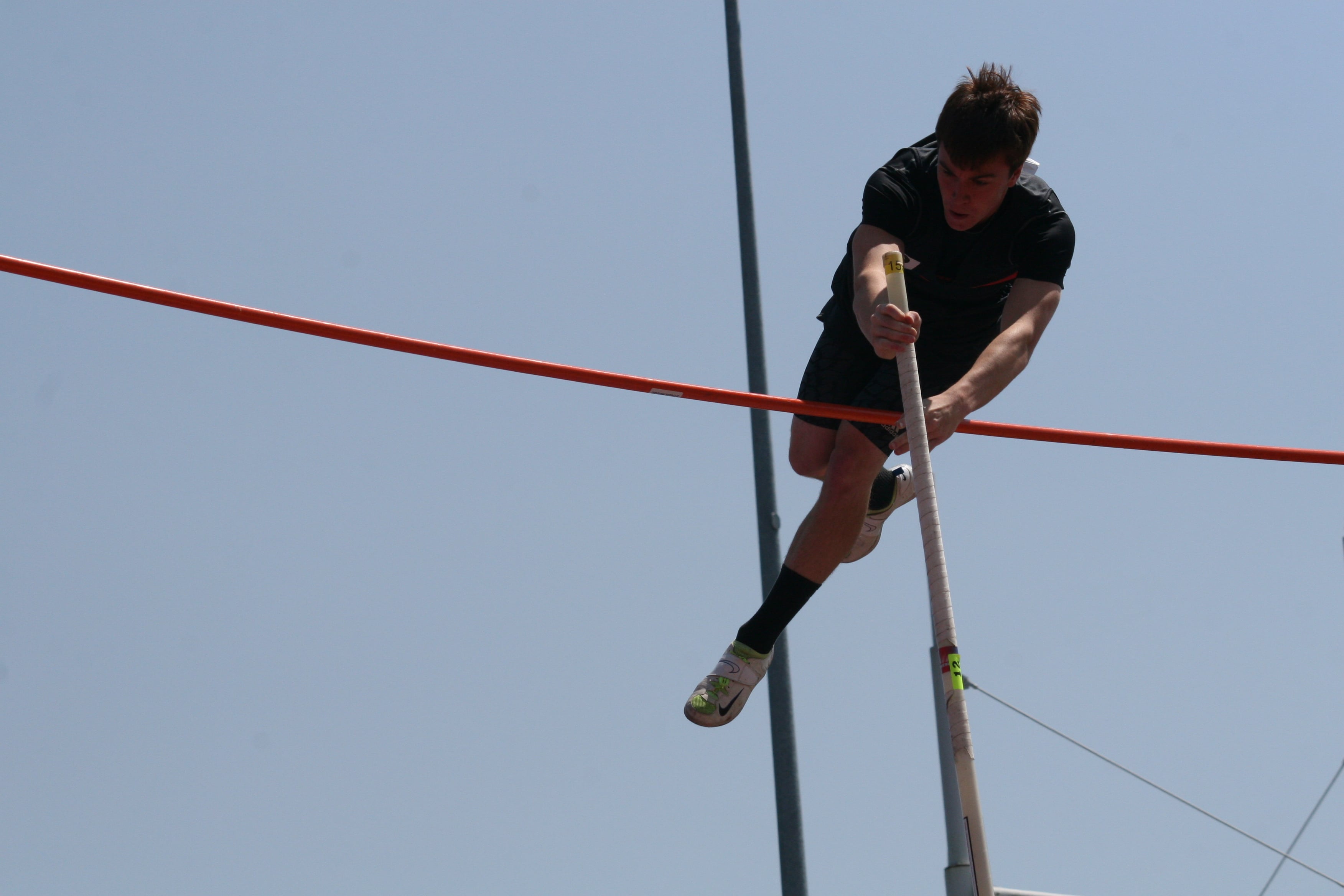 Adam Thomas lets go of the pole after he clears the bar.
