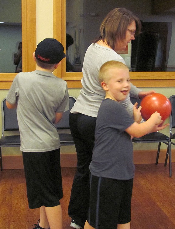 Tessa Hoff works on a back-to-back ball toss routine, designed to work the obliques, with her sons Brian, 11, (left) and Nathan, 7.