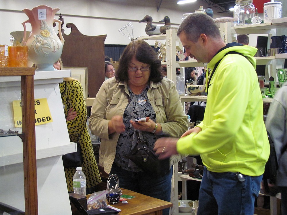 Belva Ostensen of Camas has been an antiques vendor for 27 years. Here, she assists a customer at the Clark County Antique & Collectible Show.