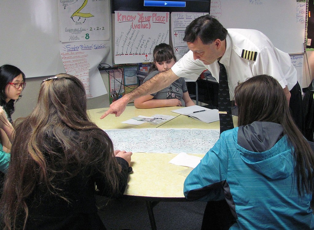 Pilot Rob Pullen shows students how pilots use special maps to determine where they are flying. He notes that GPS is used on all flights, with the maps needed only as a backup.