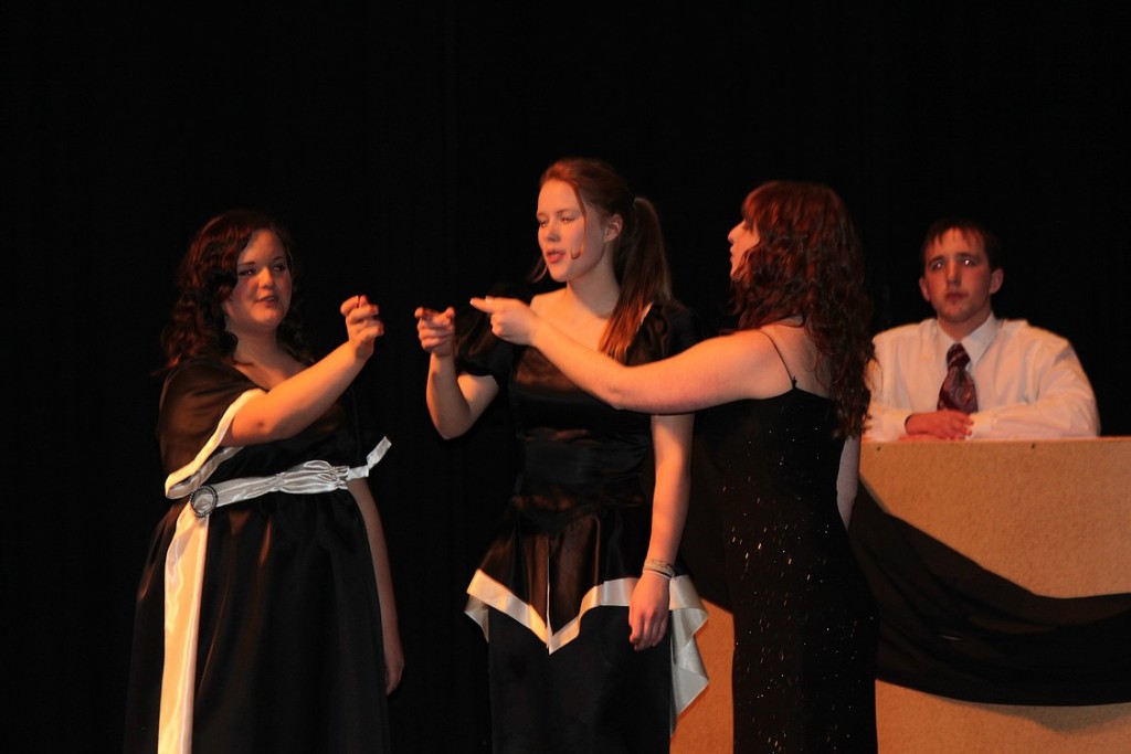 The three Witches, left to right, Lauren Tofell, Stefanie Loersch and Nicole Gamble, toast to their success while a bartender (James Stout) observes their interactions.