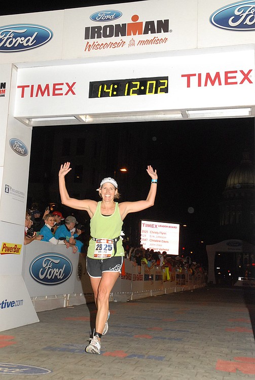 Quinn raises her arms in victory after crossing the finish line of Ironman Wisconsin in September 2010. She was severely injured in a bicycling accident this past summer, which resulted in an incomplete spinal cord injury. At first, doctors did not know if she would be able to walk again.