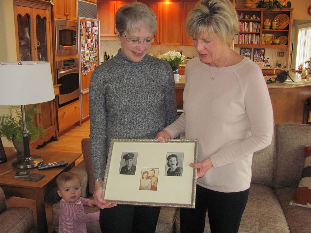 Niblock and Warner hold a photo collage of their mother and father, Luke and Laurie Snoey, when they were first married in the mid 1940s, while Warner's 1-year-old granddaughter, Lola, looks on. The family lived in Camas and owned a car dealership and repair shop on Birch Street.