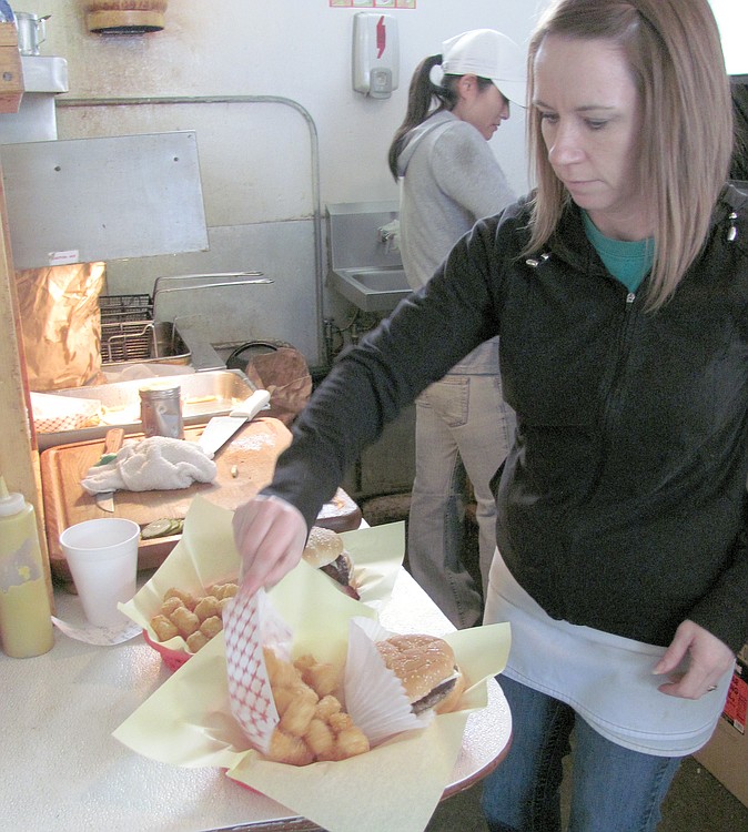 Kim Macrae-Smith, manager of the Old Fashion Maid Restaurant, cooks hamburgers on the grill, while Shelly Engel adds Tater Tots to a cheeseburger basket. Engel, 41, has worked at the 60-year old restaurant since she was 16.