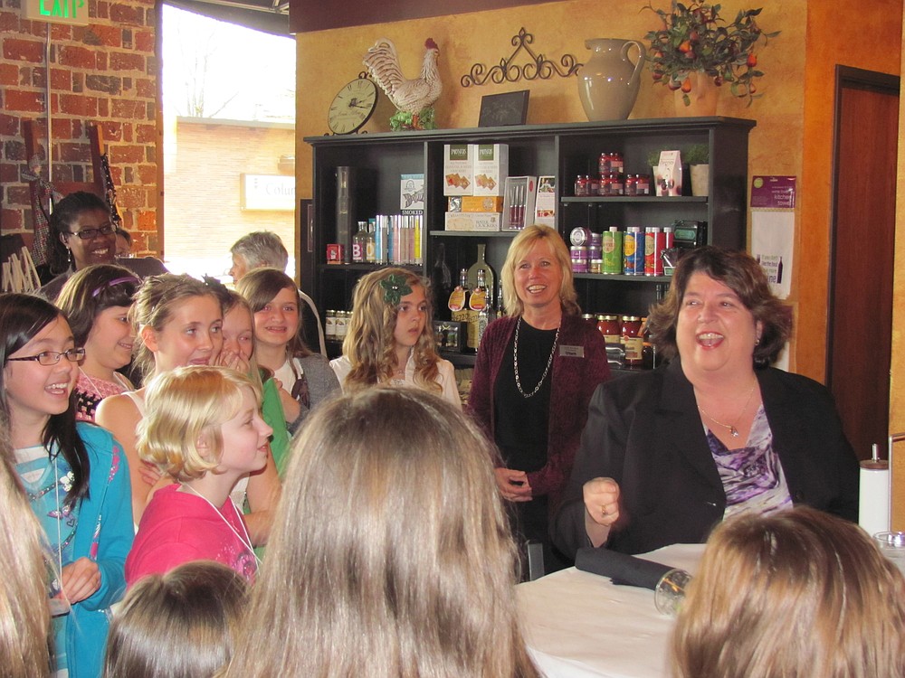 Linda Haines (seated) enjoys a laugh with several fifth-grade girls from Hathaway Elementary School during her "bad manners" skit at K'Syrah restaurant in Camas.