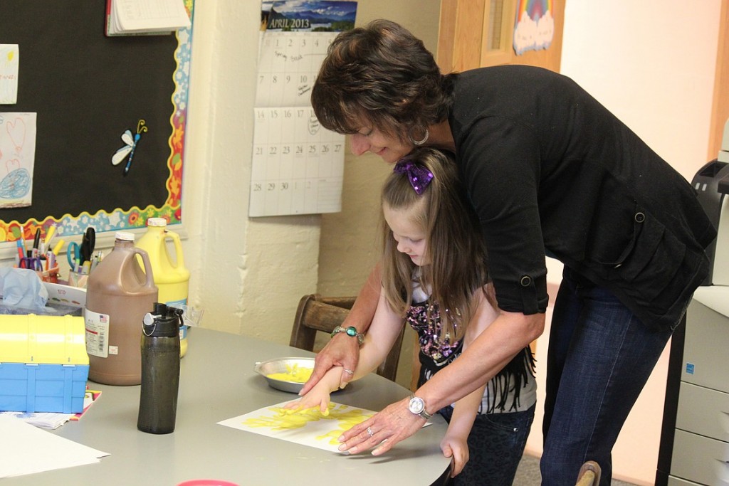 Camas-Washougal Parent Co-op Preschool teacher Maria Lattanzi helps student Fiona Robertson create a sunflower with paint. The activity was designed to complement the reading of the book, "Sunflower House." After 27 years,  Lattanzi will retire on May 22 to pursue a career in social work. "Maria truly cares for each and every student's well being," said Kara Prynne, a member of the preschool's executive board. "It shows in the way she interacts with the children on a daily basis."
