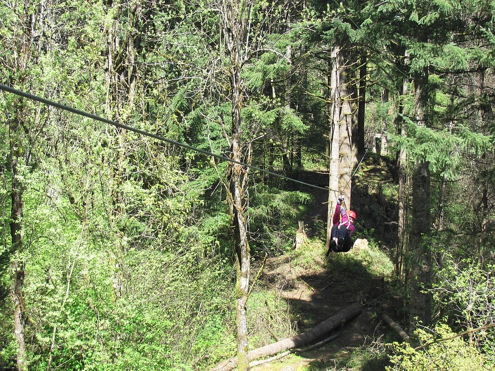Patty Hastings, a reporter with The Columbian, experiments on ways to speed up her zip line experience. Guides advise bringing your knees up and leaning back to pick up speed.