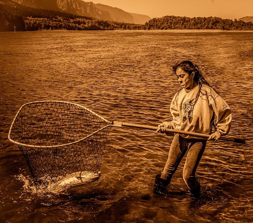 A young member of The Confederated Tribes of Warm Springs helps to land a salmon caught by her younger brother. Photographer Brian Christopher has spent two years capturing images of Native Americans at work and play, which will be on display at the Second Story Gallery in Camas.