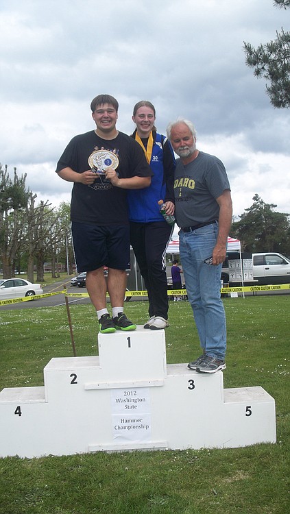 Camas hammer throwers Triton Pitassi (left) and Rachel Martschinske (center) stand on the podium with coach Hank Midles (right) May 27, at the state meet in Centralia. Pitassi captured the championship trophy and Martschinske finished in fifth place.