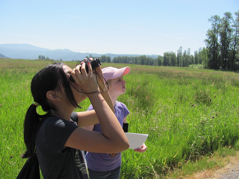 Emmy Campen (front) and Shelby Jolly search for birds during a nature walk at Steigerwald Lake National Wildlife Refuge, located just east of  Washougal.