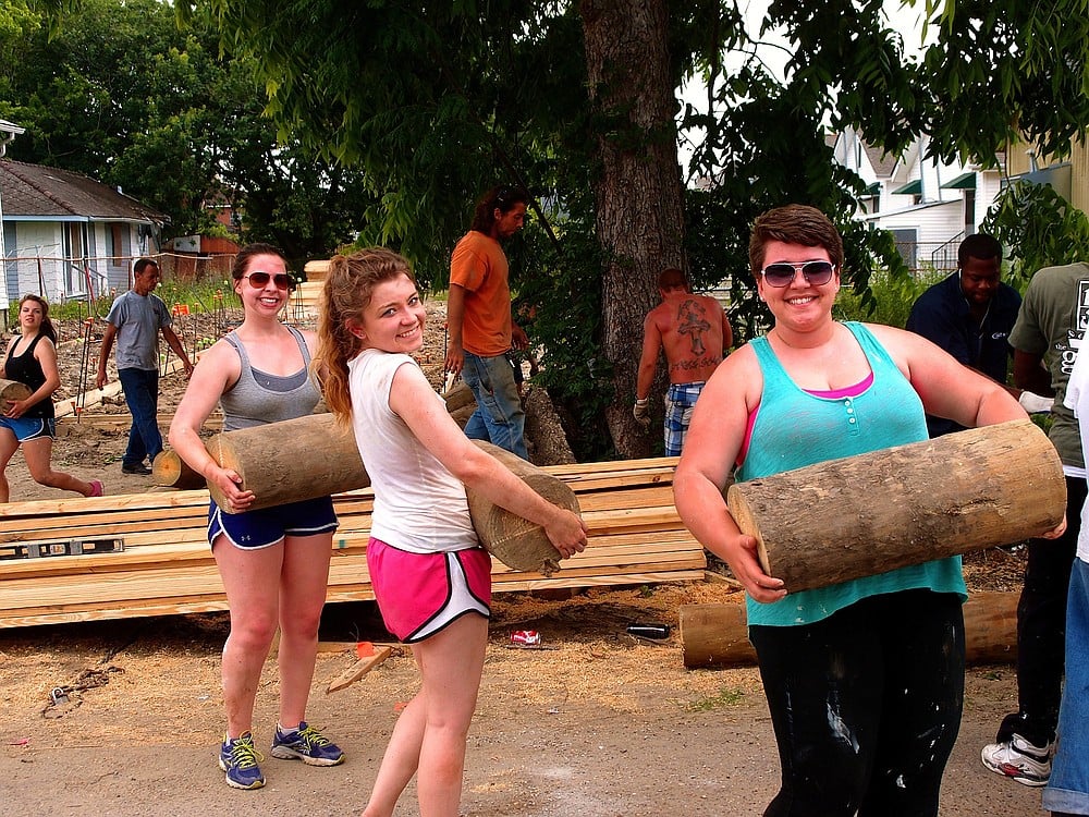 Hay (center) helps remove tree trunks from a yard while working with Habitat for Humanity in New Orleans.