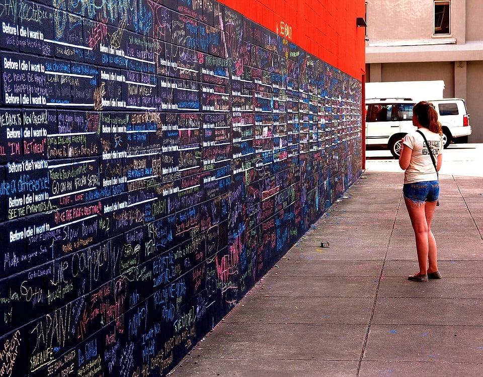 Nicole Hay contemplates on the sentences written on the "Before I Die," wall.  The wall began when a woman in New Orleans wrote on an abandoned house. Soon, other people began writing what they wanted to do before they died. Eventually, it was moved to the outside wall of the art museum downtown New Orleans, which houses the "30 Americans" exhibit of  African American art over the past century.