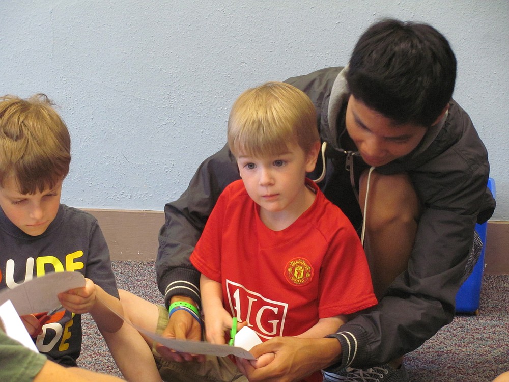 Perry Truong, 17,  helps a young attendee cut out a drawing of a plant during the Backyard Scientists summer camp.