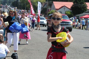 Kloe Leonard, 7, doles out candy to spectators at the Camas Days main parade on Saturday, as other members of the Georgia-Pacific Camas mill float, Anna Fry (white pants) and Sabrina Fraidenburg (pink skirt) hand out rolls of toilet paper. The Camas Days theme was rock 'n' roll.