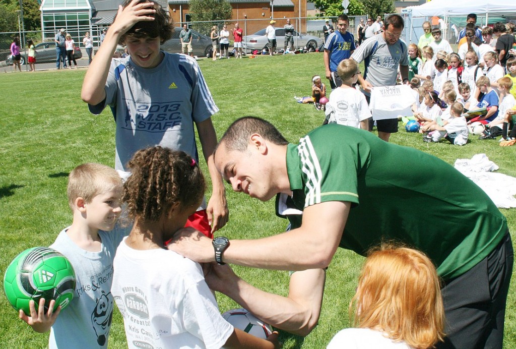 Portland Timbers soccer player Brent Richards, a Camas native, signs autographs and Dan Macaya (background) hands out shirts for the 10th anniversary of his soccer camp in Camas.