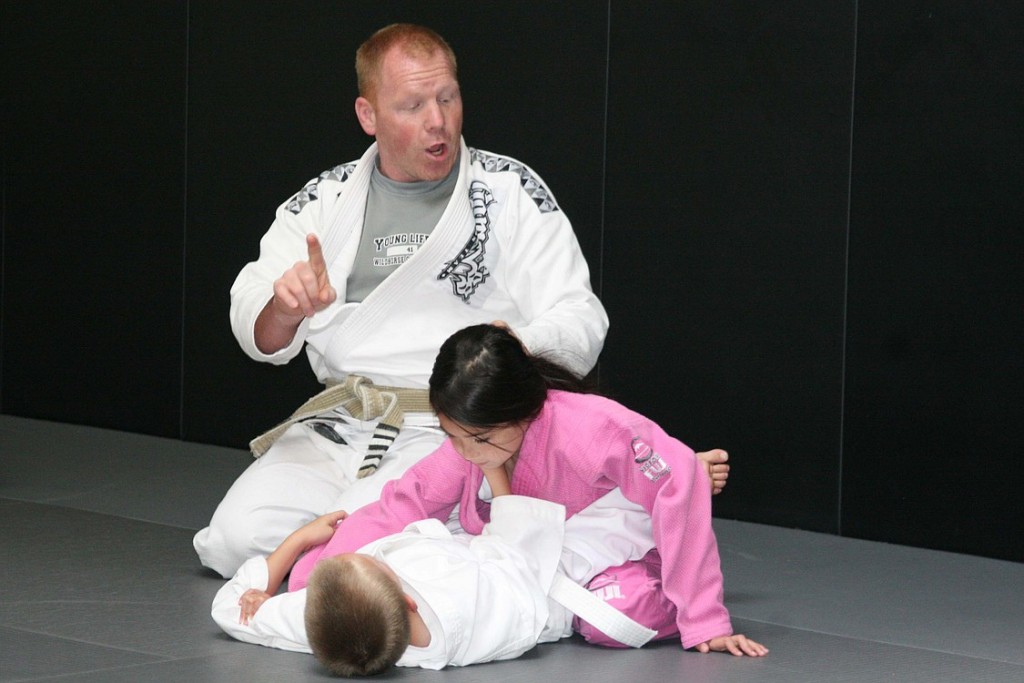 Universal MMA co-owner Mel Locke shows two youngsters Brazilian Jiu Jitsu moves.