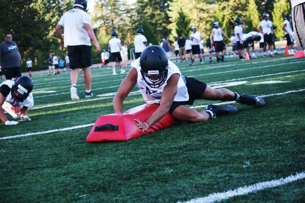 Manase Nguamo and the Camas High School football players take turns plowing over tackling pads during the first week of practice at Cardon Field.