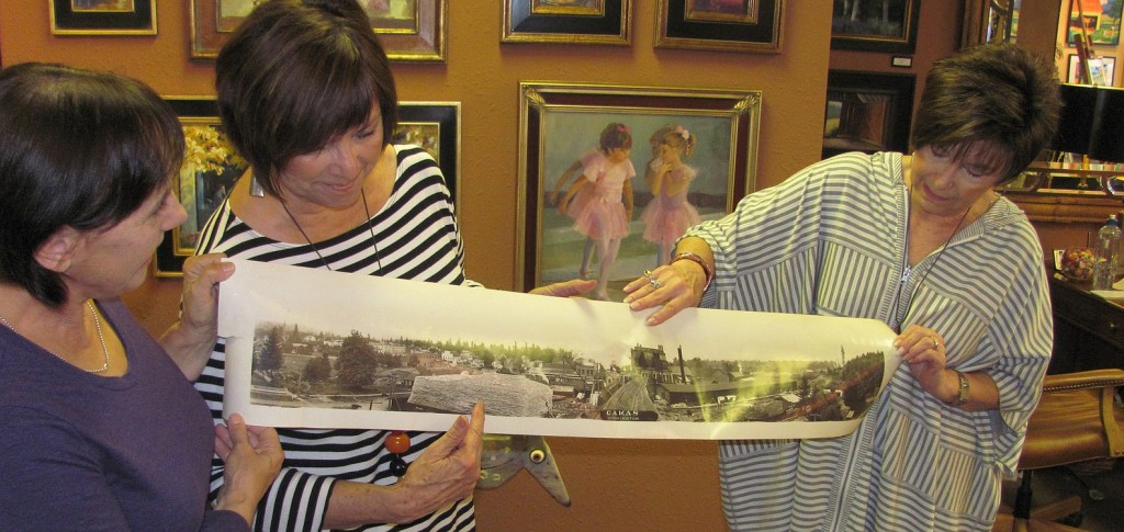 Artist Maria Repetto and downtown Camas art gallery owners Sharon Ballard and Marquita Call (left to right) hold the photograph that is the inspiration for the first mural that will be part of the Camas-Washougal Mural Project. The image of downtown Camas was taken in 1911 or 1912 from Northwest Sixth Avenue and Division Street, according to the picture's owner Brent Erickson. The mural will be painted by Repetto and mounted on a 3 foot by 30 foot space above the entry to the Ballard & Call Fine Art Gallery. The unveiling is expected to occur this fall.