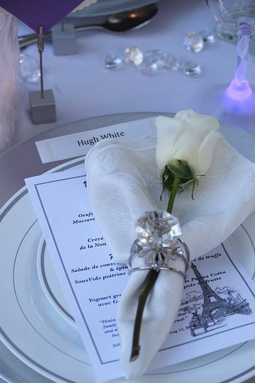 A table setting created by friends and neighbors of the Lacamas Shores neighborhood included menus printed with the Julia Child quote: "Dining with one's friends and beloved family is certainly one of life's primal and most innocent delights, one that is both soul-satisfying and eternal." Sarah Bang said each of the 16 seats at the table included a place card printed with a fictional name reflecting the "white" theme of the evening.  The Lacamas Shores group won the table decorating contest.