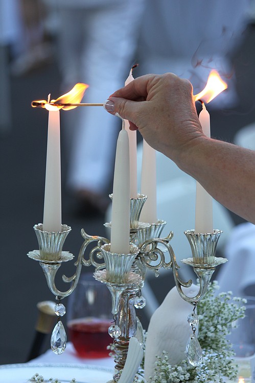Camas resident Cindy Ontkean puts the finishing touches on her table setting by lighting the white candlesticks of  a silver candelabra.