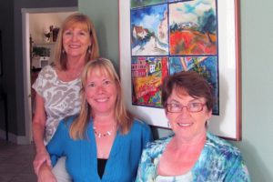 Kathy Sork, AnnaMarie "Suzy" Clement and Linda McCulloch (left to right) pose by a six-paneled group watercolor they helped create. The other artists who painted panels were Julianne Schreiner, Carolyn Gunderson and Judith Sanders-Wood.