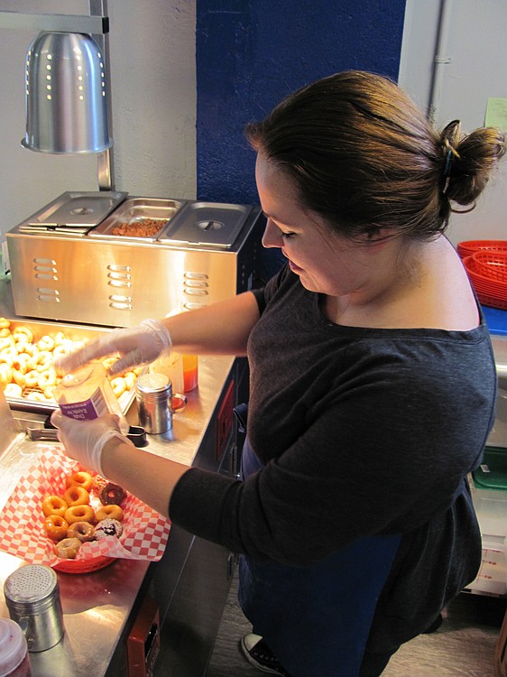 Sarah Arnold, co-owner of Echo Donut Lounge, in downtown Washougal, adds toppings to mini doughnuts. She and Bret Van Horn use a Lil' Orbits SS1200 mini-donut machine. "It is capable of making up to 1,200 donuts per hour, although we don't ever run it that hard," Van Horn said.