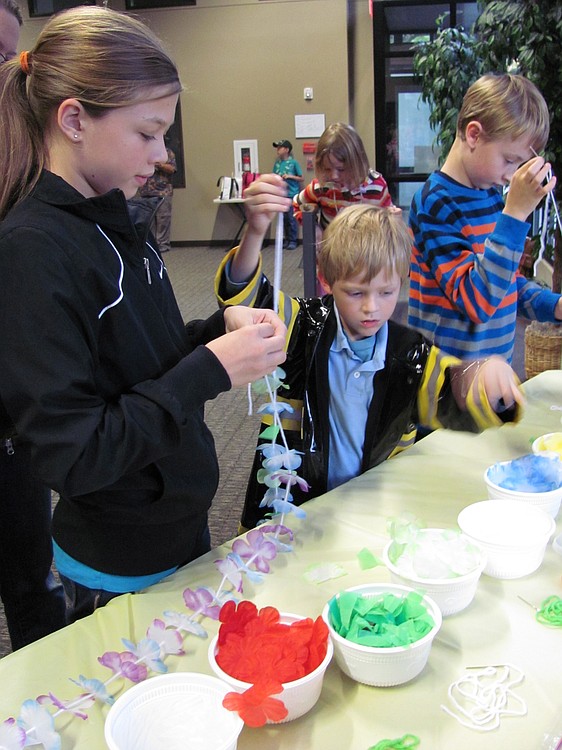 Children participate in a Hawaiian-themed craft activity during the "Pineapples in Peril" party.
