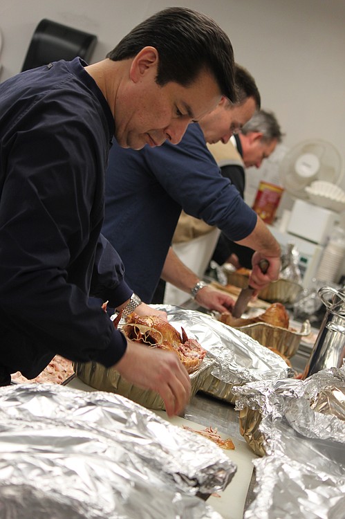 Members of the Knights of Columbus, including Ernest Pittaway (front) and Michael Rollins (center), packed the kitchen at St. Thomas Aquinas Catholic Church on Wednesday night. The group spent several hours carving more than 50 turkeys that were donated from individuals and non-profit organizations. The Knights of Columbus, a Catholic men's service organization, reaches out in other ways too. Each winter, they distribute 20 to 25 cords of wood to families in need. The wood is donated by private property owners as well as local school districts and city governments, when the wood becomes available on their properties.