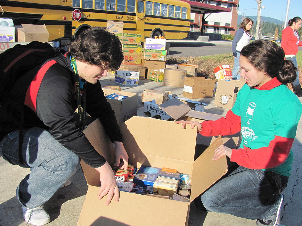 Camas High School students Tyler Hows and Maiah Sharma help sort boxes of food during the annual Stuff the Bus event, sponsored by the Camas-Washougal Business Alliance.