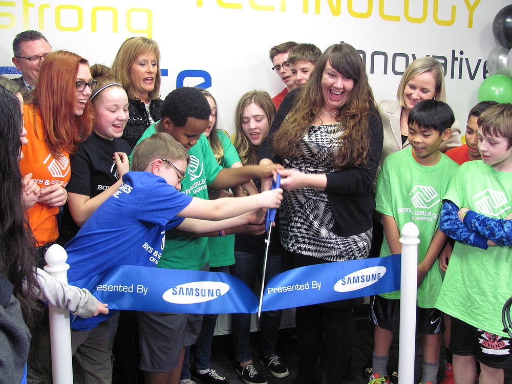 Amber Barnes, unit director for the Jack, Will and Rob Boys & Girls Club, is assisted by club members during the  ribbon cutting ceremony for the new Tween Tech Center on Tuesday.