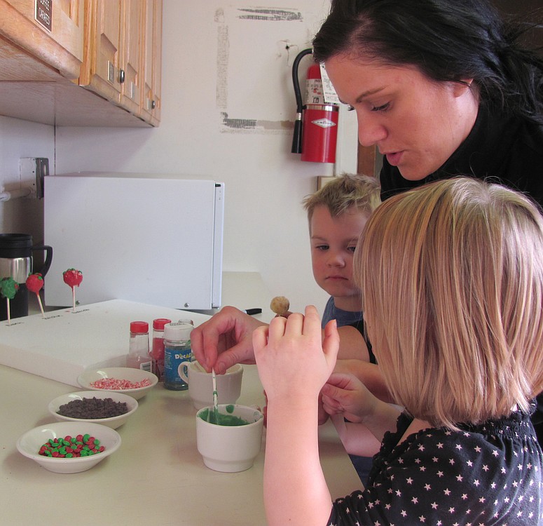 Winter break camp recreation leader Melissa Levison helps two young campers make cake pops at the Camas Community Center.