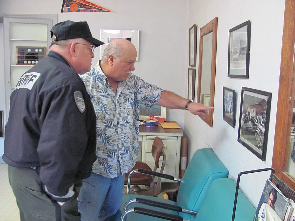 Retiring Clark County Sheriff Garry Lucas (left) recently looked at historical photos of downtown Camas, with Lyle Shaver (right), former owner of Sportsman Barber Shop. That business is located at 214 N.E. Fourth Ave., next to the former site of Cowan's Cigar Store, a tavern restaurant that was owned by Lucas' father, Donald Lucas, and uncle, Lamont "Smokey" Lucas, from the mid-1940s to the early 1950s.
