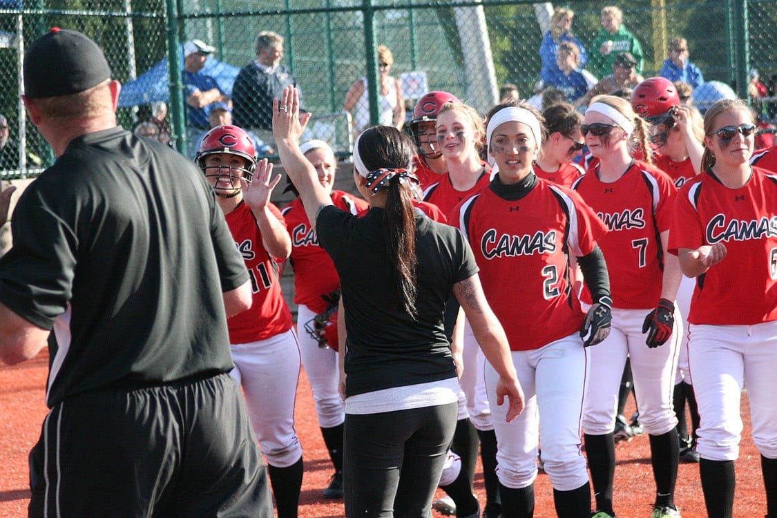 Mikaela Searight celebrates with her teammates and coaches at home plate.