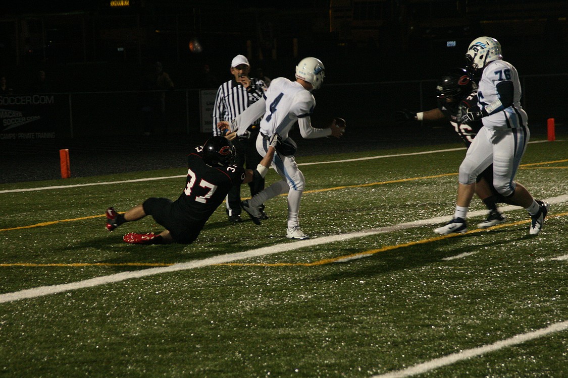 Kyle Goodnow drags the Meadowdale quarterback into the end zone, while John Ashford comes charging in from the right.