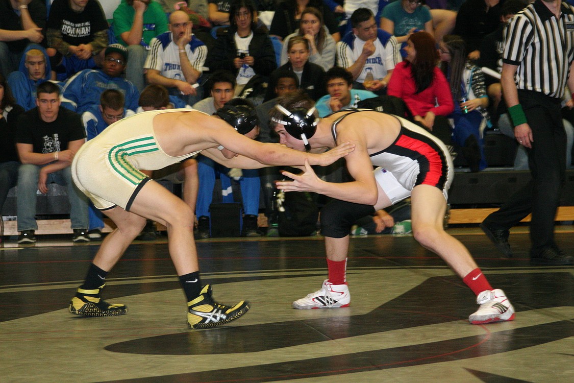 Camas wrestler Marcus Hartman (left) locks up with defending state champion Michael Nguyen (left) of Evergreen.