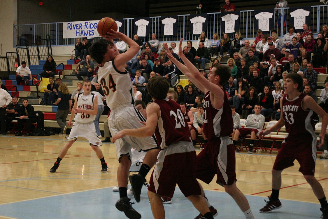 Aaron Deister shoots over two defenders and scores two points.