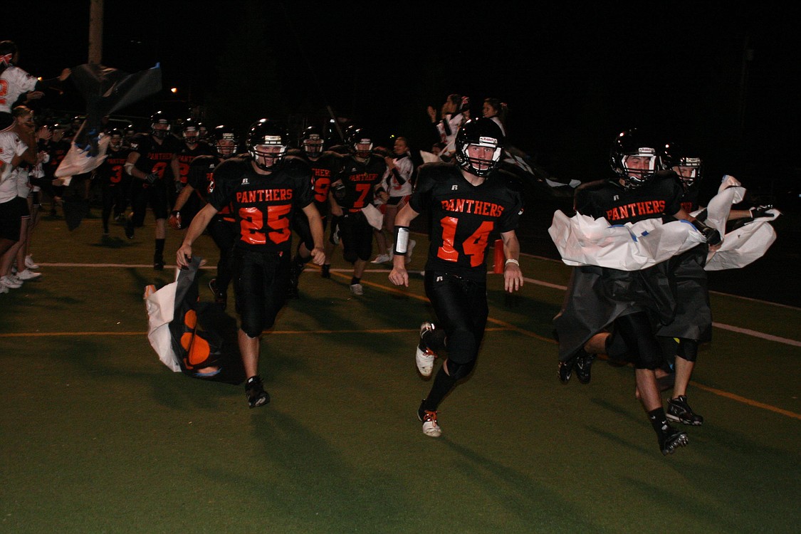 The Washougal High School football players rip through a banner on their way back out to Fishback Stadium to begin the second half.