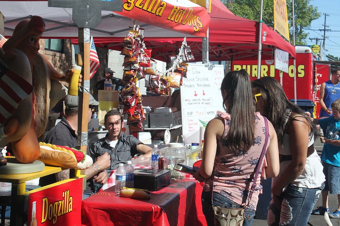 Eric DeRoos of Dogzilla Hot Dogs assists two Camas Days patrons last Friday. Food offerings ranged from unique doughnuts to Vietnamese fare, with tempting smells wafting through the air.