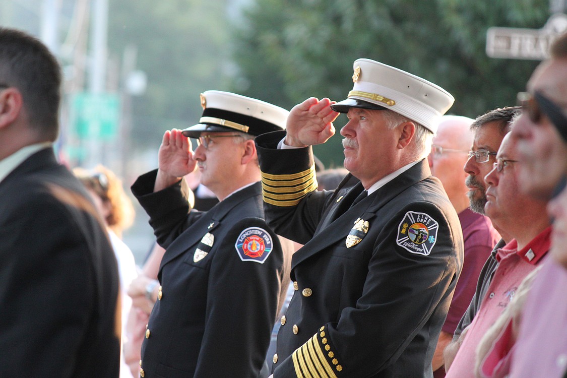 Washougal Fire Chief Ron Schumacher (right) and Longview Battalion Chief Kevin Taylor (left) stand at attention as Camas Battalion Chief Allen Wolk and Camas Fire Capt. Chuck Bettis (not pictured) raise the American flag to half-mast in front of the Camas Public Library Sunday morning, in recognition of the 10-year anniversary of the Sept. 11, 2001, terrorist attacks.