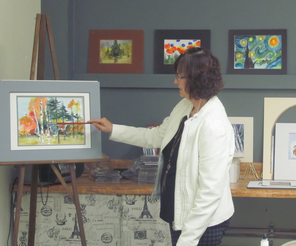 Nancy Ryan demonstrates a painting technique during a recent class. Behind her is student artwork.                                